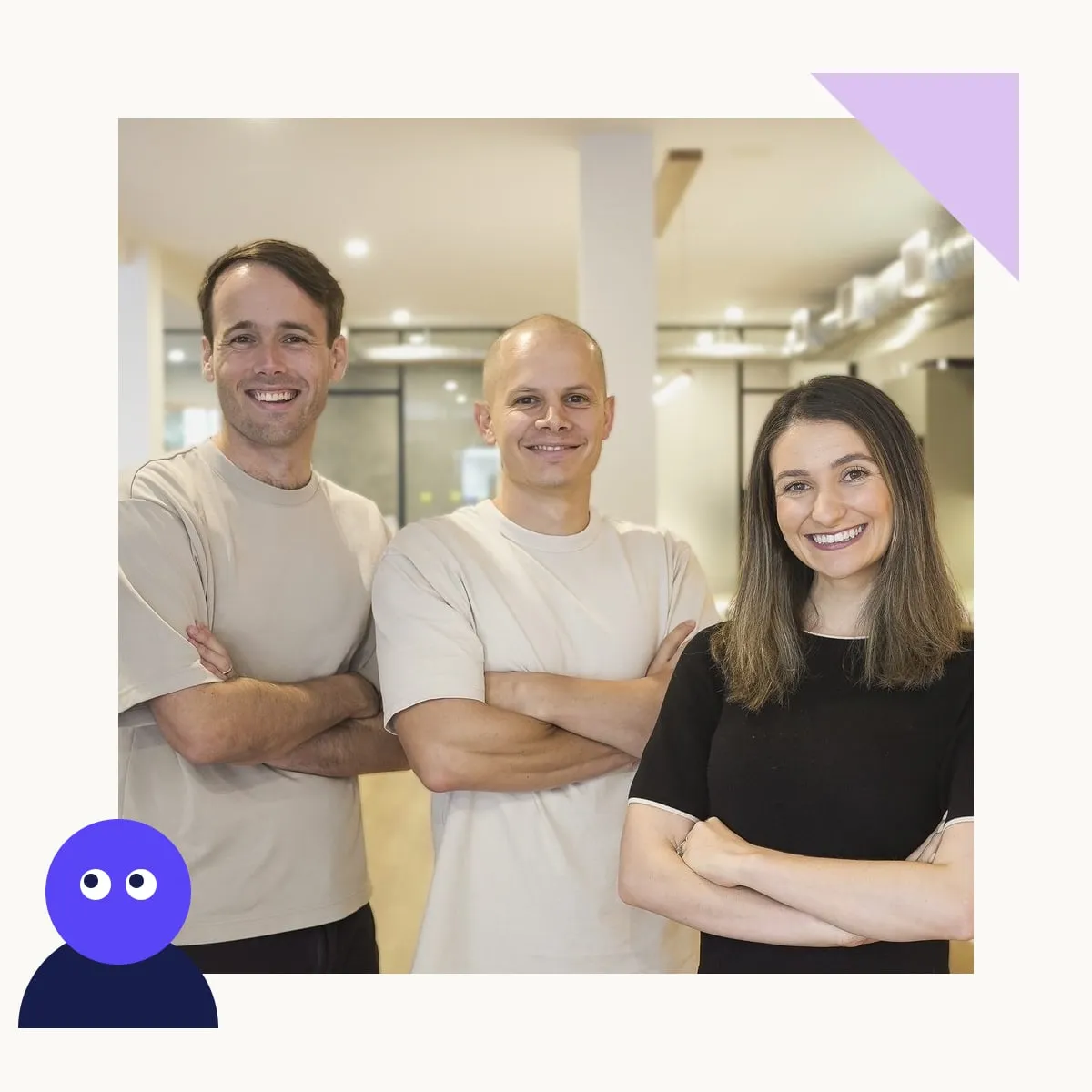Three smiling team members standing with arms crossed in a bright office