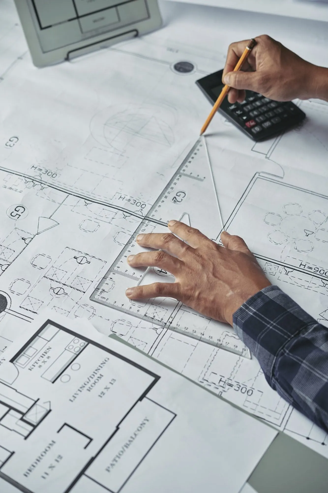 Hands working through a floor plan with a pencil and calculator