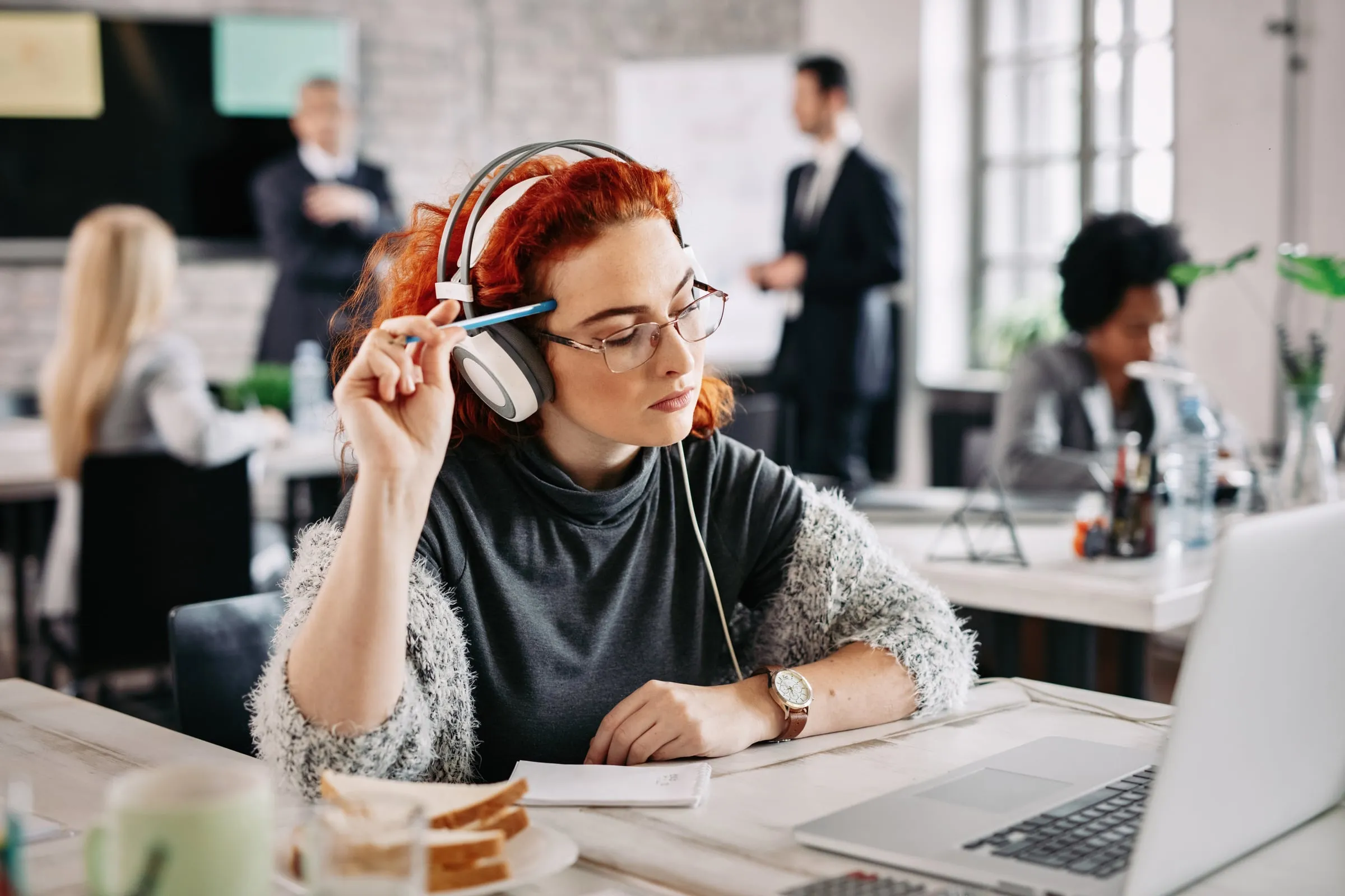 A woman with headphones concentrating on her laptop