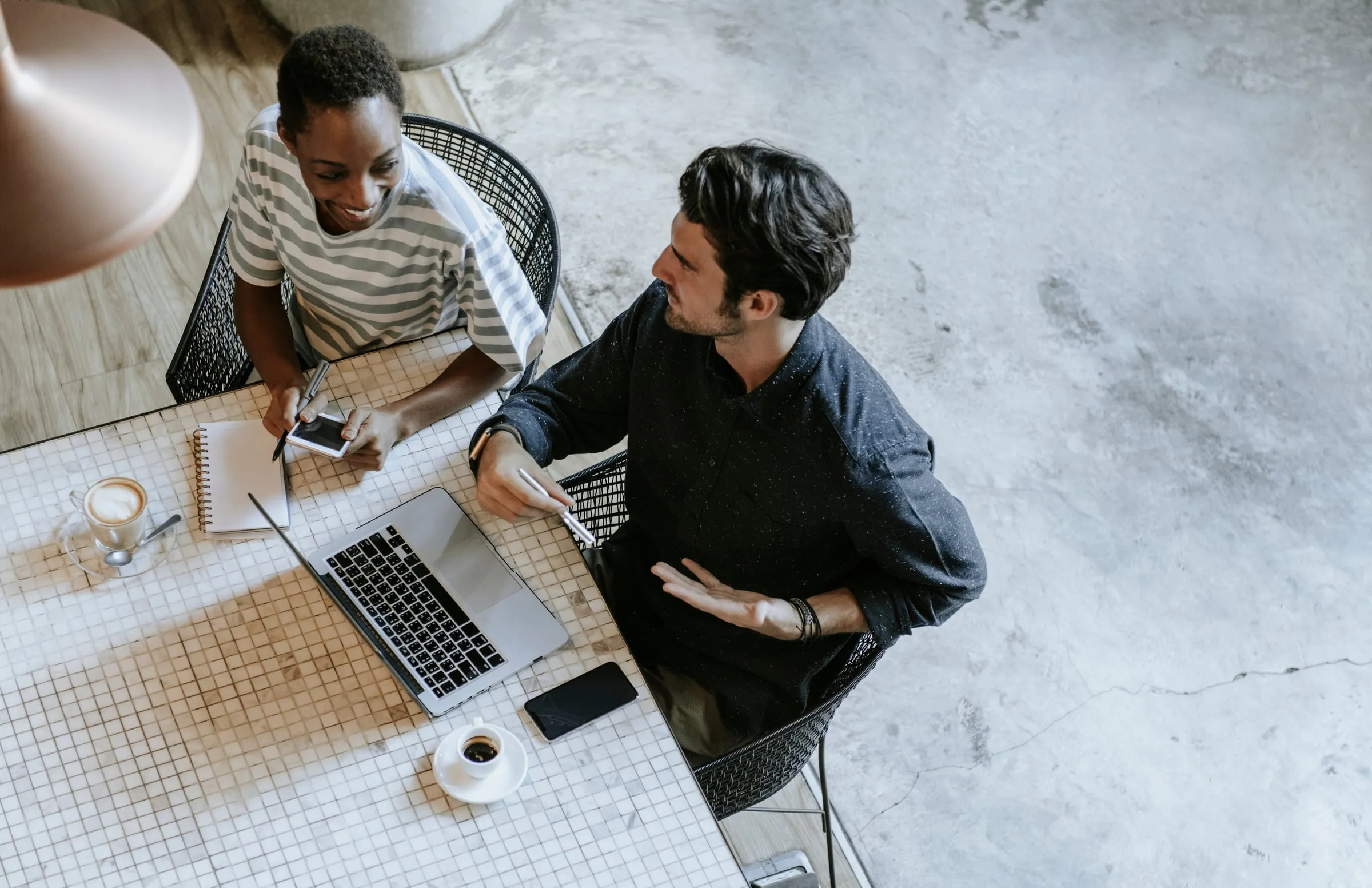 Two people talking over a laptop in a cafe